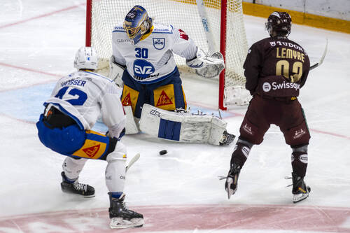 Tobias Geisser (EVZ), gauche, lutte pour le puck avec Tristan Lemyre (GSHC), droite, avant le gardien Leonardo Genoni (EVZ), centre, lors du match du championnat suisse de hockey sur glace de National League entre Geneve-Servette HC, GSHC, et EV Zug, EVZ, ce dimanche 4 octobre 2026 a la patinoire de la Les Vernets a Geneve . (KEYSTONE/Martial Trezzini)