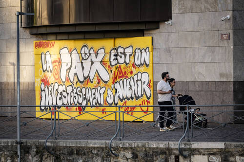 People walk past graffiti against the upcoming G7 summit, in Geneva, Switzerland, Friday, June 12, 2026. (KEYSTONE/Jean-Christophe Bott)